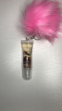 a bottle of lip balm with a pink furry pom pom